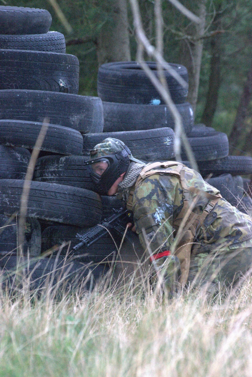 Paintball player crouched behind a tyre barricade