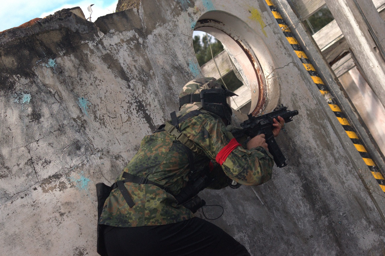 Paintball player aiming through field cover